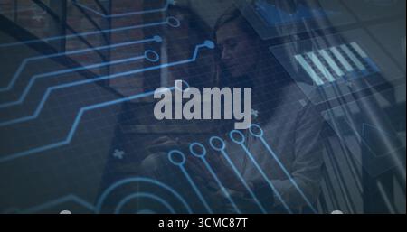 Collaborating colleagues using tablet-laptop on office stairwell, with blue circuit board overlay Stock Photo