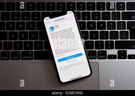 iOS 26 software update displayed on iPhone over Apple laptop keyboard, full device view in light mode. Stafford, United Kingdom, September 15, 2025 Stock Photo
