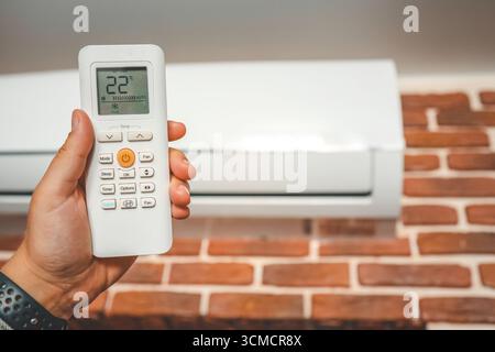 Hand with remote control directed on the conditioner. Stock Photo