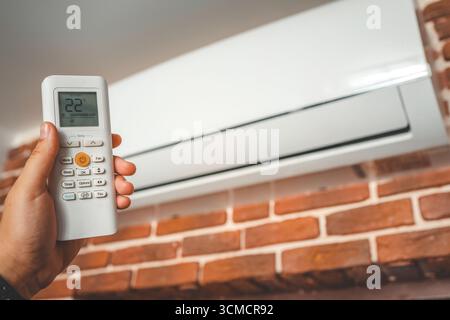 Hand with remote control directed on the conditioner. Stock Photo
