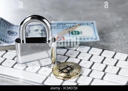 Cyber safety. Metal padlock, bitcoin, dollar banknotes and computer keyboard on grey table, closeup Stock Photo