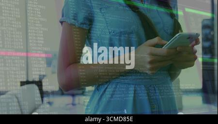 Hispanic woman wearing denim dress checking smartphone in modern office, with code overlay Stock Photo