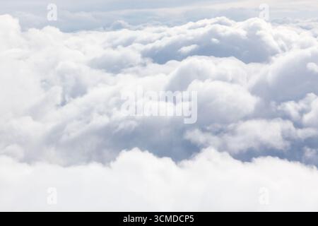 An aerial view captures a thick, white layer of fluffy clouds. Sky is barely visible between the dense cloud formations. Stock Photo