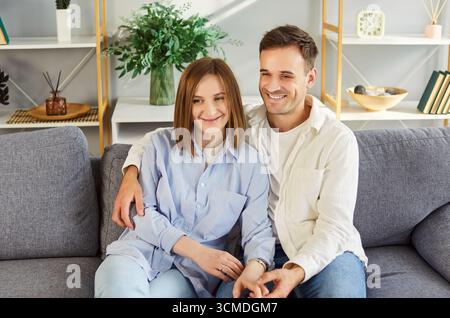 Home portrait of happy young married couple in love posing for photo seated on couch Stock Photo