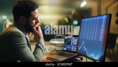Businessman, thinking and night with stock market screen for monitoring graph, statistics or data. Man, broker or trader working late with computer Stock Photo