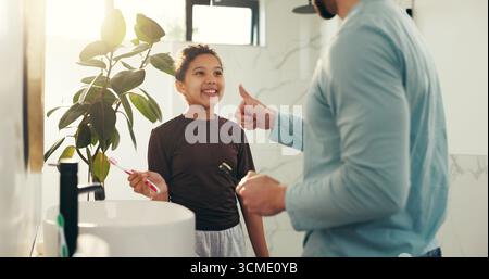 Child, father and brushing teeth with thumbs up in bathroom for fresh breath, oral hygiene and teaching. Family, girl and man for dental health Stock Photo