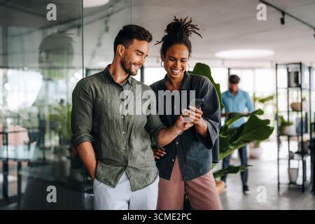 Cheerful diverse coworkers having fun during work break using technology enjoying working together Stock Photo