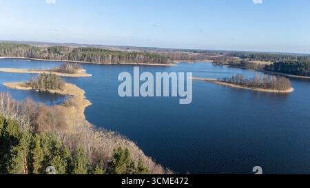 Aerial view of a serene lake with a small island, a fountain, and dense ...