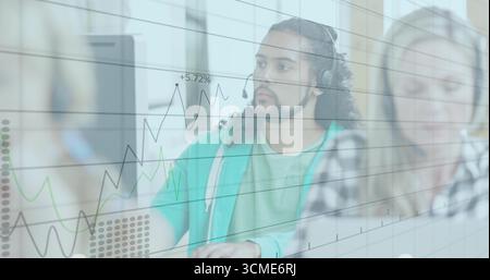 Staring curly-haired agent wearing green hoodie at center workstation, with monitors and headsets Stock Photo