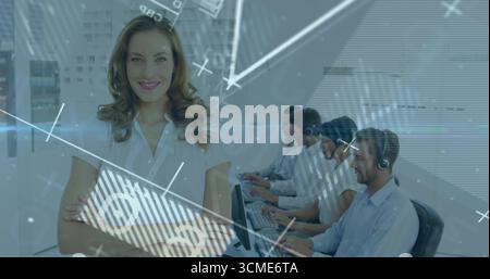 Smiling supervisor wearing white blouse crossing arms in call center with monitors, copy space Stock Photo
