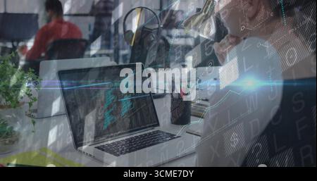 Typing developer wearing headphones entering code on laptop at open-plan office, with pen holder Stock Photo
