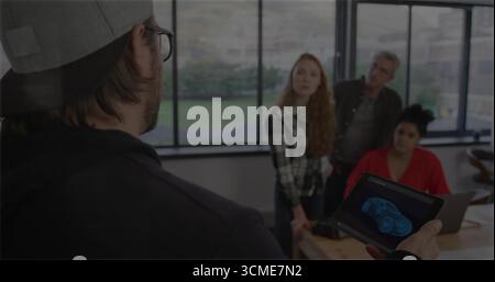 Presenting man demonstrating car wireframe on tablet at meeting table, with laptop copy space Stock Photo