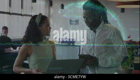 Collaborating two office professionals analyzing digital data overlay in office with laptop, tablet Stock Photo