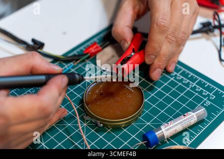 Hands working with soldering iron and wires for electronic repair Stock Photo