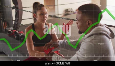 Wrapping male trainer securing red hand wraps on boxer inside ring amid kettlebells, with overlay Stock Photo