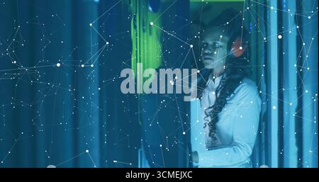 Two IT techs inspecting server racks in data center with headphones, network overlay, copy space Stock Photo