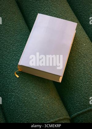 White book on green background. Book with completely blank white cover is placed on a green cloth surface. Stock Photo