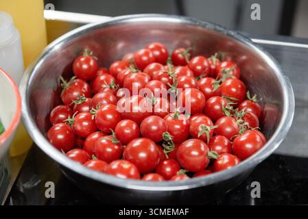 sliced ​​cherry tomatoes in an iron bowl Stock Photo