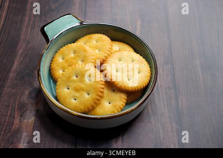Light golden salted crackers with sprinkled salt on top. styled as a tea time snack. comfort food and savory bakery items. Crisp salted round biscuits Stock Photo