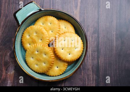 Light golden salted crackers with sprinkled salt on top. styled as a tea time snack. comfort food and savory bakery items. Crisp salted round biscuits Stock Photo