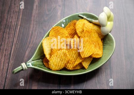 Spicy masala potato chips with golden crisp texture served in a bowl, sprinkled with tangy seasoning, perfect for snack, fast food, or tea-time Stock Photo