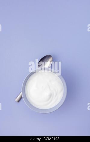 Fresh natural yogurt in blue bowl on blue background Stock Photo