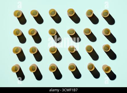 Uncooked Rigatoni pasta with shadows arranged in rows on light green background Stock Photo
