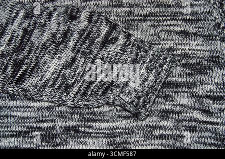 Close-up texture of a grey and white knitted wool fabric background. Seamless macro view of marled knit pattern material for sweater, clothing, and te Stock Photo