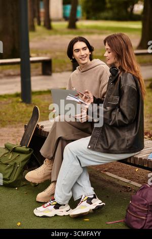 Two individuals share smiles and laughter on a sunny day in the park while studying together. Stock Photo