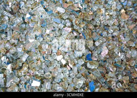 Colorful shattered glass pieces shining with blue, gold and silver reflections. Close-up texture ideal for abstract backgrounds and modern digital art Stock Photo