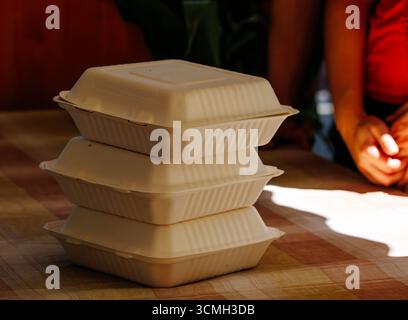 Stack of three eco-friendly biodegradable takeout containers on table with blurred background. Stock Photo