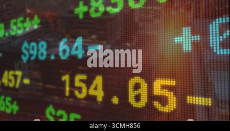 Displaying stock market data on dotted LED grid at dusk skyline, with digits and symbols Stock Photo