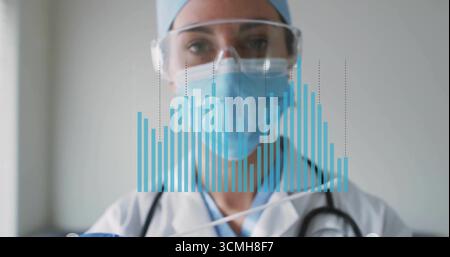 Displaying physician wearing labcoat and mask with stethoscope viewing digital bar chart in clinic Stock Photo