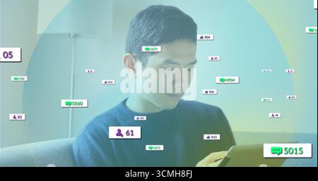 Reviewing tablet Asian man sitting on sofa under floor lamp in living room, with digital overlays Stock Photo