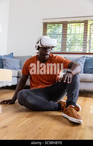 Virtual reality headset resting on hardwood floor in living room with sofa and cushions Stock Photo