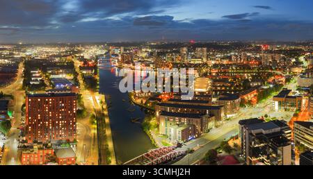 Twilight aerial view of Salford Quays and River Irwell in Manchester with glowing city lights reflecting on the water. Stock Photo
