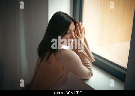 Young thoughtful woman in a long dress in the studio. Light thoughtfulness and dreaminess Stock Photo