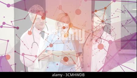 Three medical professionals reviewing data on tablet in hospital corridor, with stethoscopes Stock Photo