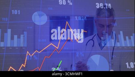 Reviewing male doctor taking notes on tablet in clinic, with stethoscope and digital data overlays Stock Photo