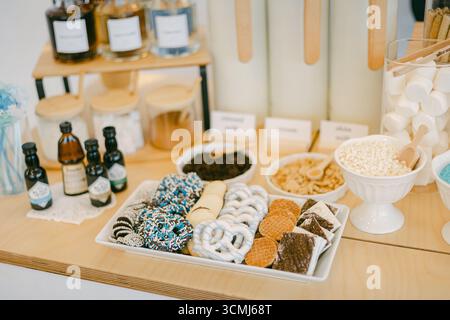 Assorted desserts and snacks arranged on a table in a lively cafe, inviting visitors to indulge in a sweet experience. Stock Photo