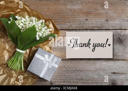 Thank you card, flowers and gift box on wooden background Stock Photo