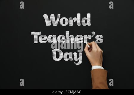 Happy Teacher's Day greeting card. Woman writing text on blackboard, closeup Stock Photo