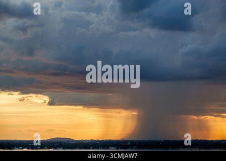Miami Beach Florida,weather storm clouds rain shaft thunderstorm rainfall heavy downpour,sunset golden sky dramatic light rays,rain curtain isolated s Stock Photo