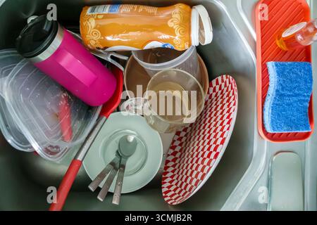 Miami Beach Florida,kitchen sink,dishwashing chores,dirty dishes utensils cups mugs,plastic containers,coffee creamer bottle,red and white patterned p Stock Photo