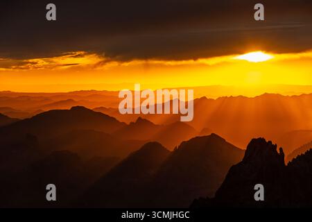 Dramatic sky and orange sunset over a layered mountain landscape, KOFA National Wildlife Refuge Mountains, Arizona, USA Stock Photo