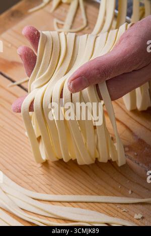 Close-up of a person holding fresh homemade tagliatelle pasta Stock Photo
