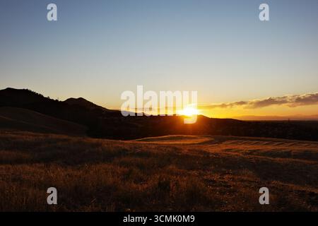 Fiery sunset skies and twilight over the rolling hills of Contra Loma in Antioch, California. The East Bay landscape is captured in vibrant colors Stock Photo