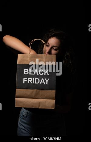 Woman holding a black friday shopping bag against a black background Stock Photo
