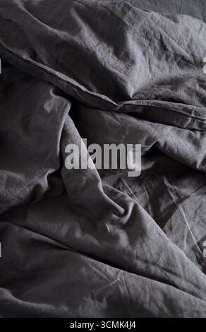 Close up view of crumpled fabric showing texture and shadow. Natural surface for clothing design elements. Abstract gray background. Stock Photo