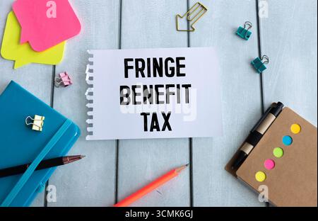 On the table are reports, a magnifying glass, a calculator, a pen, and a white notebook with the text FBT Fringe Benefit Tax Stock Photo